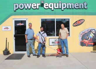 Three people in front of RJ's Power Equipment store
